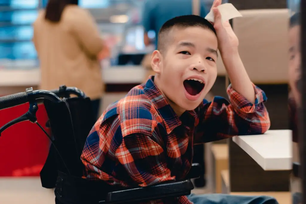 Disabled child on wheelchair waiting for a meal at the table